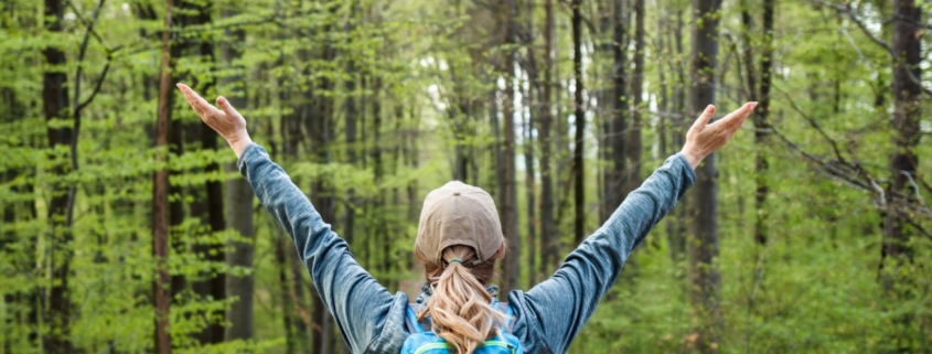 Happy woman enjoying hiking in forest