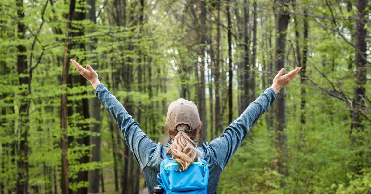Happy woman enjoying hiking in forest